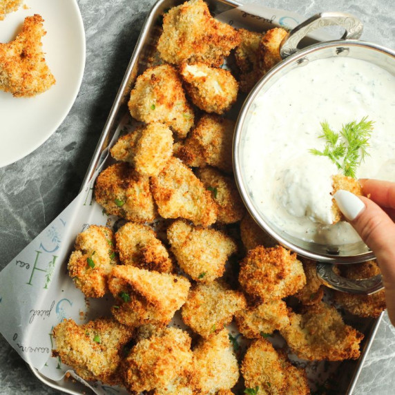 Crispy cauliflower being dipped in homemade ranch for game day food ideas.