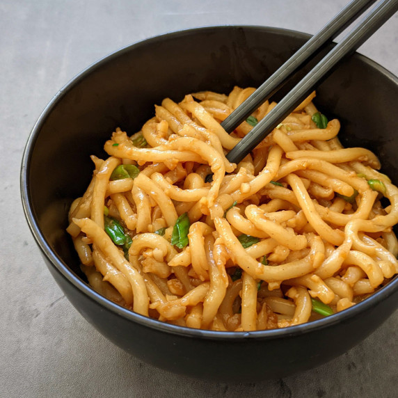A bowl of thick and chewy Asian garlic noodles served with chopsticks
