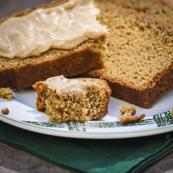 Close up shot of two slices and a small piece of ginger loaf with apple butter cream cheese.