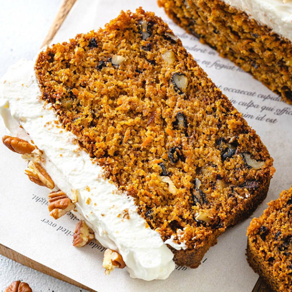 Photo of two slices of carrot cake loaf decorated with frosting and chopped pecans
