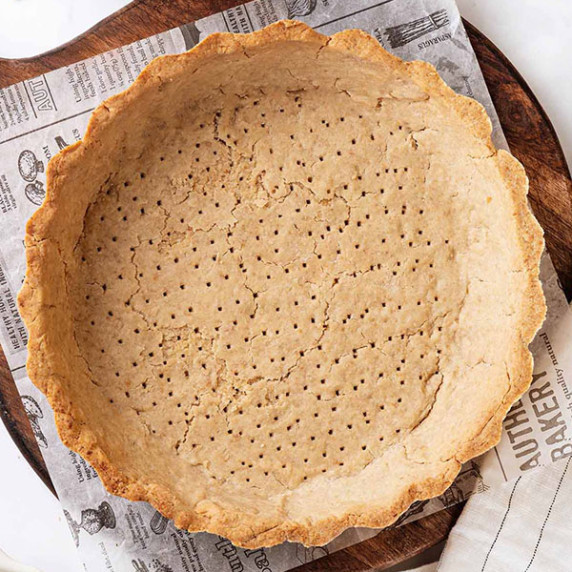 Prebaked gluten-free pie crust on a wooden board