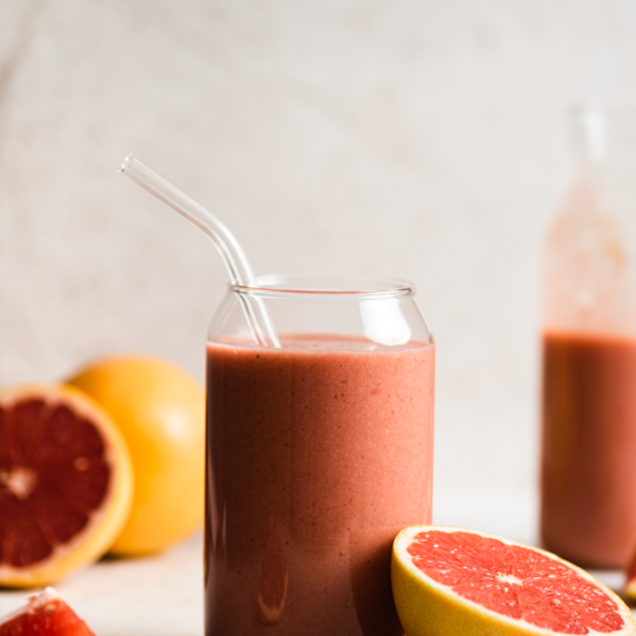 Grapefruit smoothie arranged in an aesthetic glass with straw and a grapefruit on the side