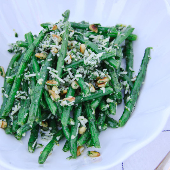 green beans with pine nuts, cheese and parsley served on a plate