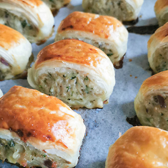 Rows of small sausage rolls on a baking tray