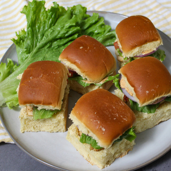 A plate of grilled chicken sliders with fresh lettuce on brioche dinner rolls