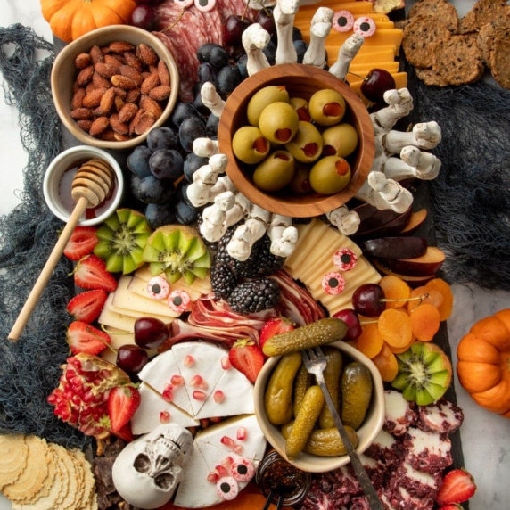 A Halloween themed charcuterie board with cheeses, meats, and snacks decorated with spooky decor.
