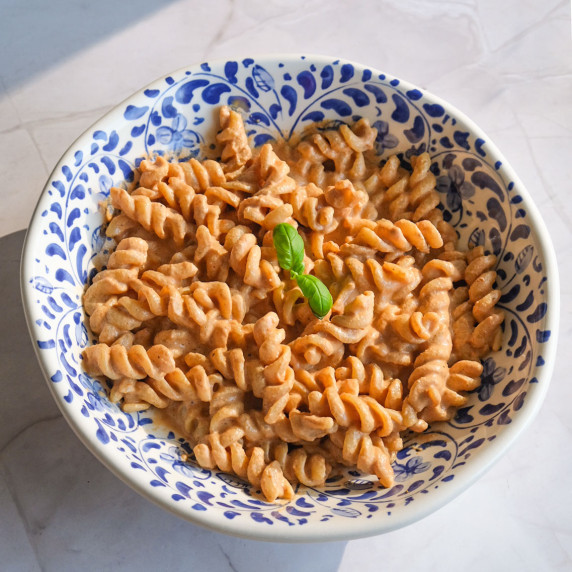 A plate with high protein pasta and a basil garnish in the middle