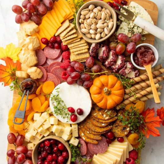 Holiday charcuterie board with meats, cheeses, crackers, nuts, and fruits arranged for Thanksgiving.