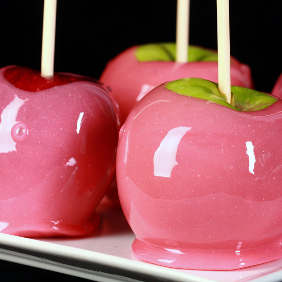3 candy apples, dipped in shiny pink candy.