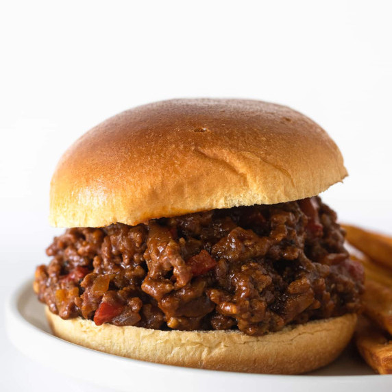 sloppy joes on a white plate with french fries.
