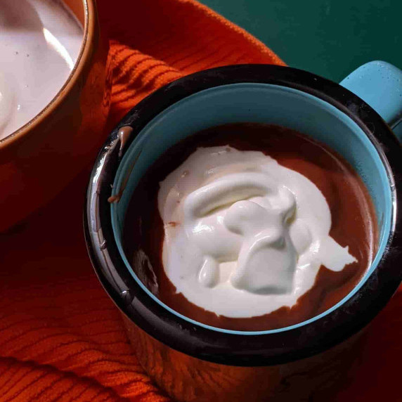 a turquoise mug of hot chocolate with slightly whipped cream