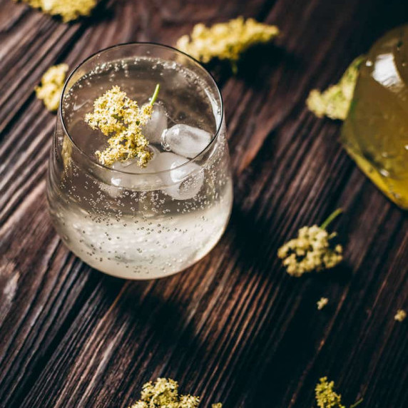 A glass cup filled with elderflower fizz mocktail on ice.