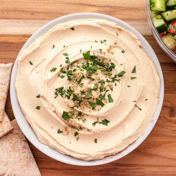 Hummus in a bowl with chopped parsley on top.