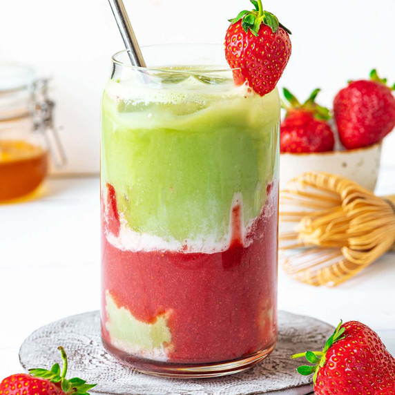 iced matcha latte with the layer of strawberry purree and milk, and decorated with fresh strawberry