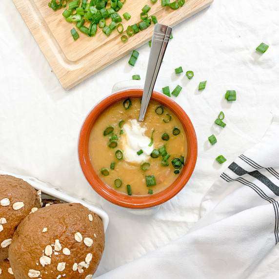 potato soup with sour cream and green onion and a basket of hearty brown rolls