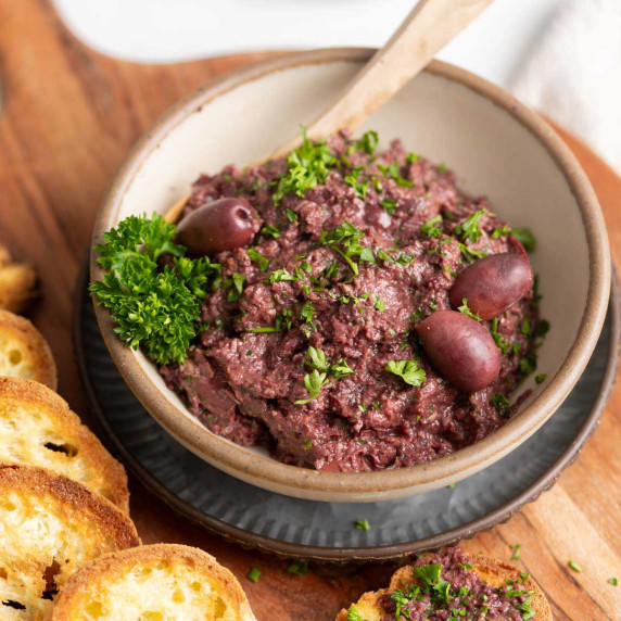 Kalamata tapenade in a bowl with fresh parsley. 