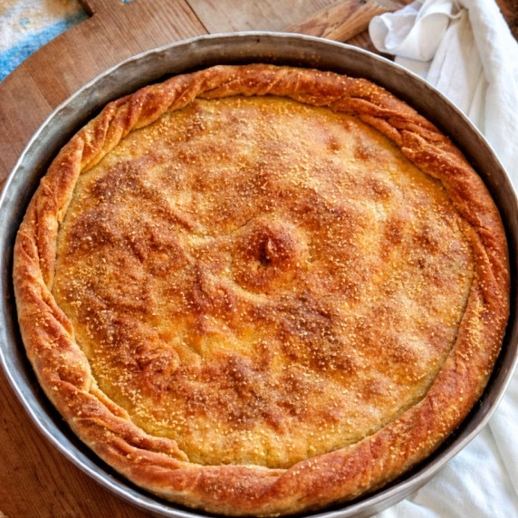 Kefalonian codfish pie with golden crust baked in a round pan.