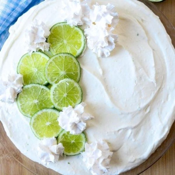 A no bake key lime pie topped with sliced limes and whipped cream.