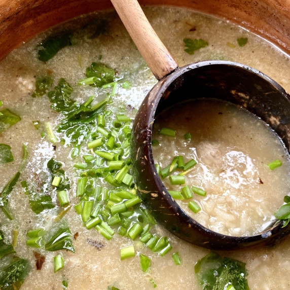 Top-down view of clay soup pot with khao tom (Thai rice soup).