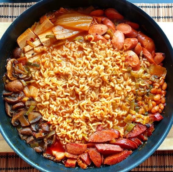 Korean Army Stew in a pot on top of a wood countertop