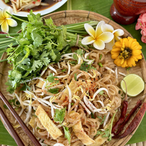 Top-view of kua mee, Lao noodles with egg, garnished with fresh herbs and spices.