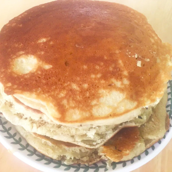 honey lavender pancakes stacked on white plate with green leaf design on wooden table