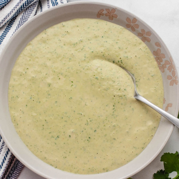 Lemon herb tahini sauce in a glass bowl with chopped cilantro.