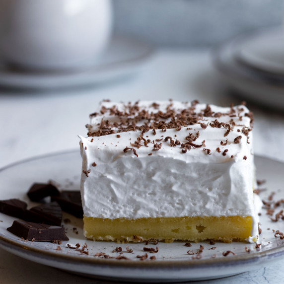 Lemon meringue slice in a plate with grated chocolate on top