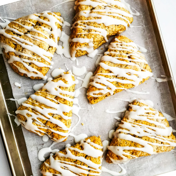 lemon poppy seed scones with drizzled icing on a baking sheet.