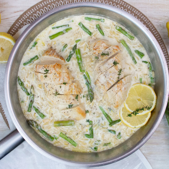 one pan with chicken breast on top of creamy orzo