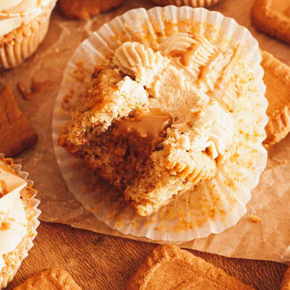 A close up of a bitten Biscoff cupcake with Biscoff filling oozing out.