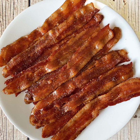 A white plate with a dozen strips of maple candied bacon.