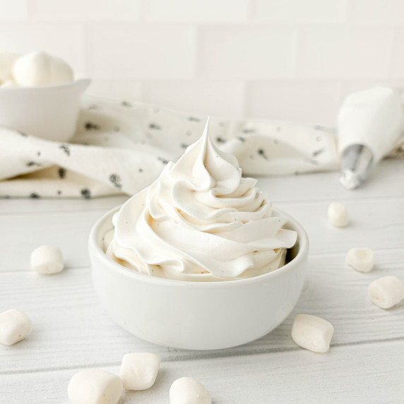 Small white bowl filled with Marshmallow Frosting with small marshmallows in the background.