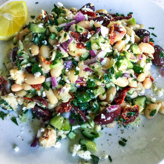 A plate of white beans, tuna, red onion, sun dried tomatoes, and kalamata olives. 