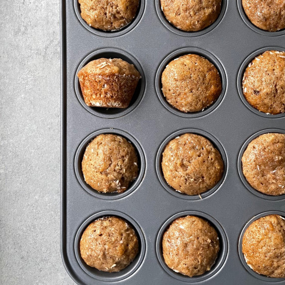 a mini muffin pan with baked mini banana muffins