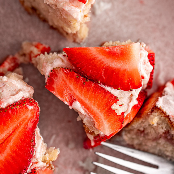 A slice of mini strawberry cake, topped with fresh strawberry slices.