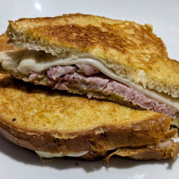 A Croque Monsieur sandwich, cut in half, and placed so you can see the ham and cheese inside.