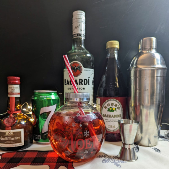 A cocktail in a Christmas glass with all the ingredients lined up behind it. 