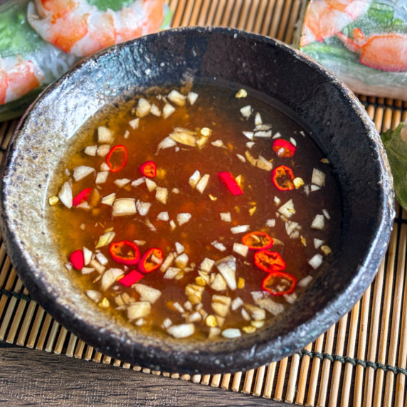 Close-up of nuoc cham, Vietnamese fish dipping sauce, in a sauce cup.