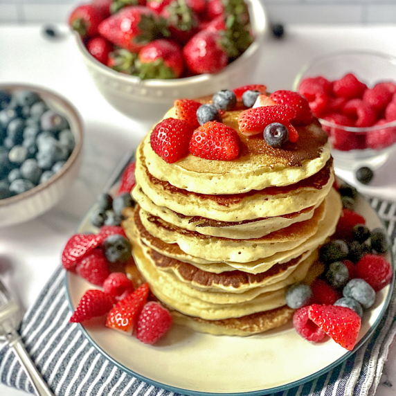 stack of oat milk pancakes topped with strawberries and blueberries