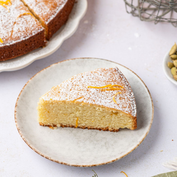 a slice of orange cardamom olive cake on a round plate