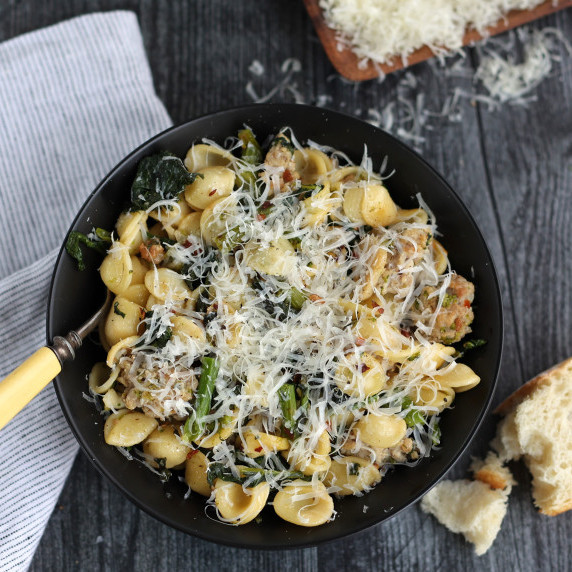 bowl of orecchiette pasta with sausage, broccoli rabe, and grated Parmesan