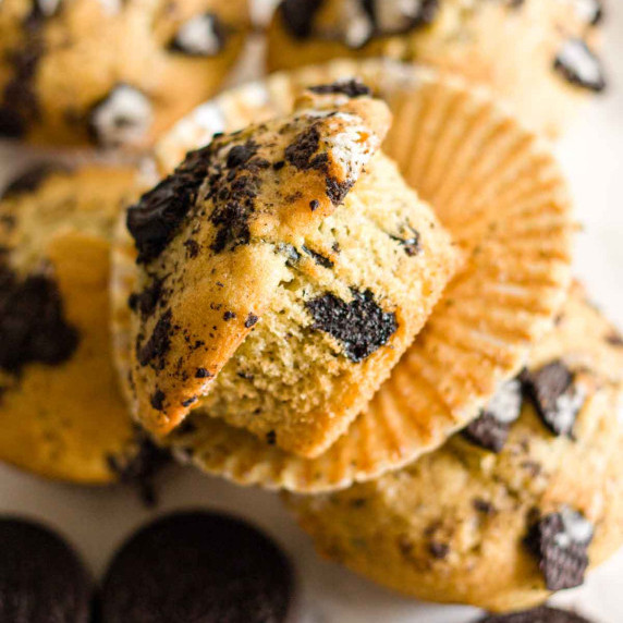 A close up of an Oreo muffin on an unwrapped liner over four muffins.