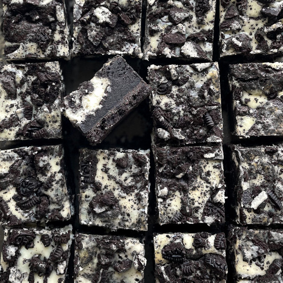 16 cut oreo cheesecake brownie bars with one turned on its side to show layers.