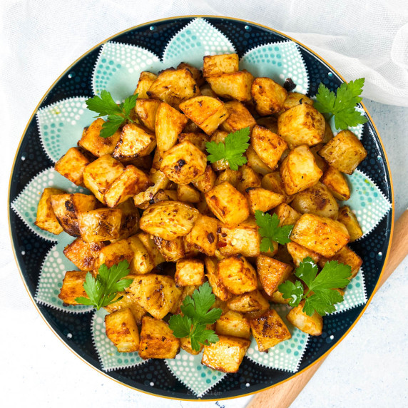 Golden looking baked potatoes on a colorful plate.