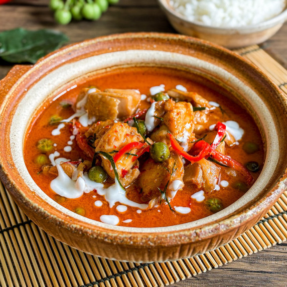 Thai panang curry with chicken and vegetables served in a traditional clay bowl.