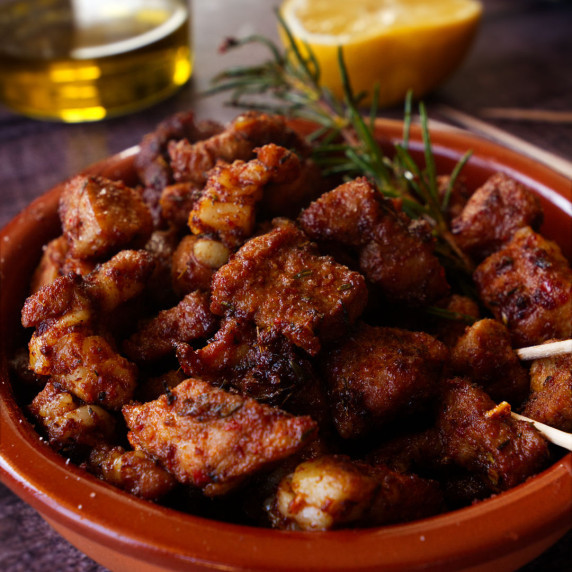 a  small tapas serving of paprika-infused pork bites sits beside a sherry and lemon