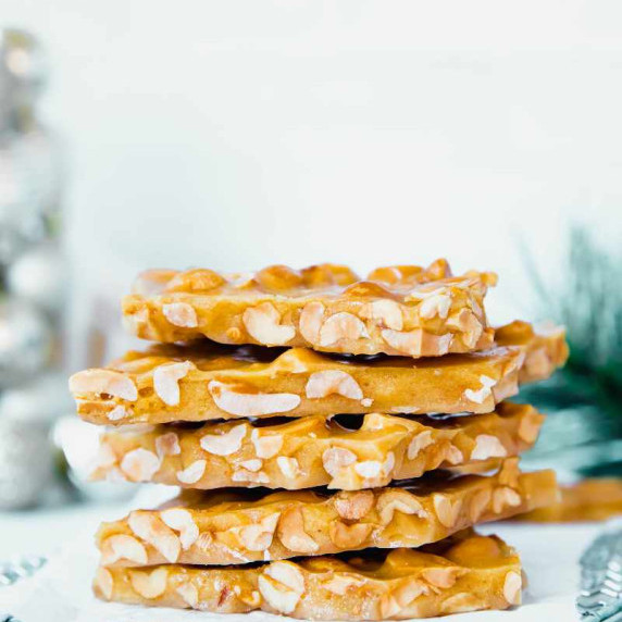 A stack of homemade peanut brittle pieces on a light background.