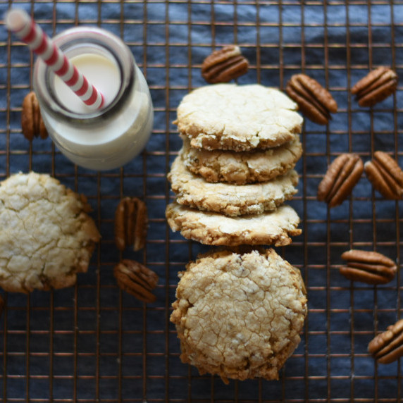 Pecans and pecan sandies on a baking rack with a bottle of milk and a red and white straw.