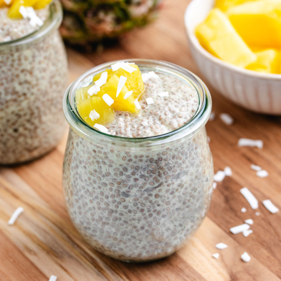 Pineapple chia seed pudding in a glass jar with diced pineapple and shredded coconut on top.